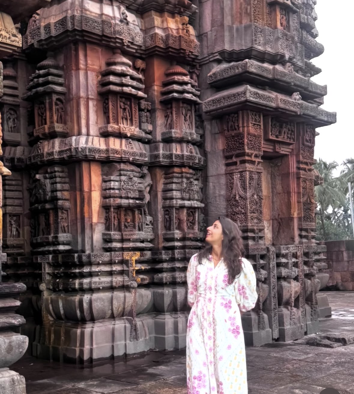 Shatakshi looking up at an ancient stone temple carved with figures
