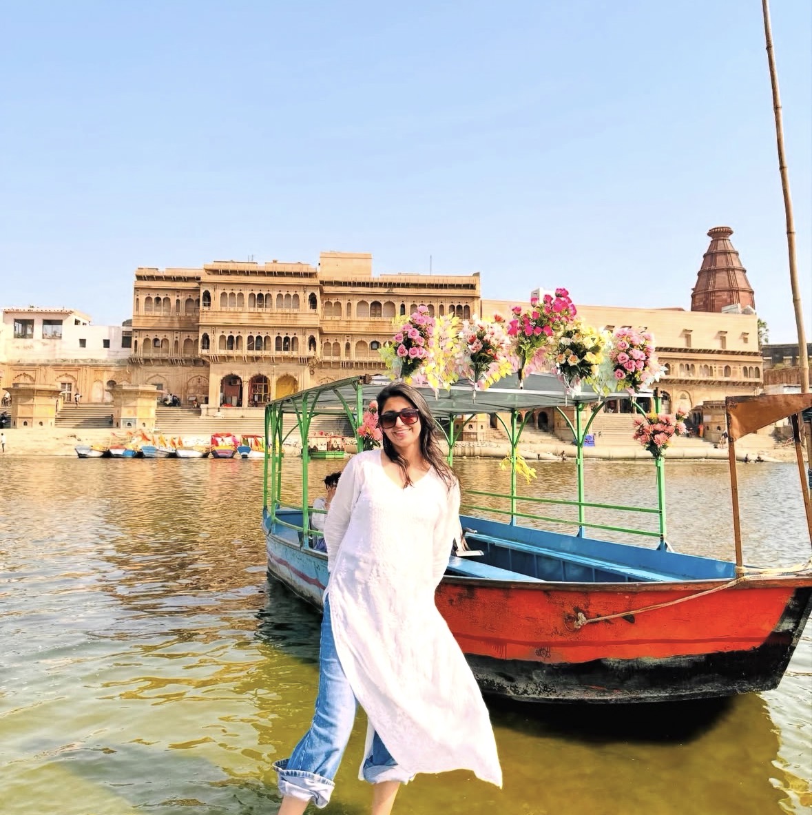 Shatakshi in a white kurta beside a flower-decked boat on the Yamuna at Vrindavan